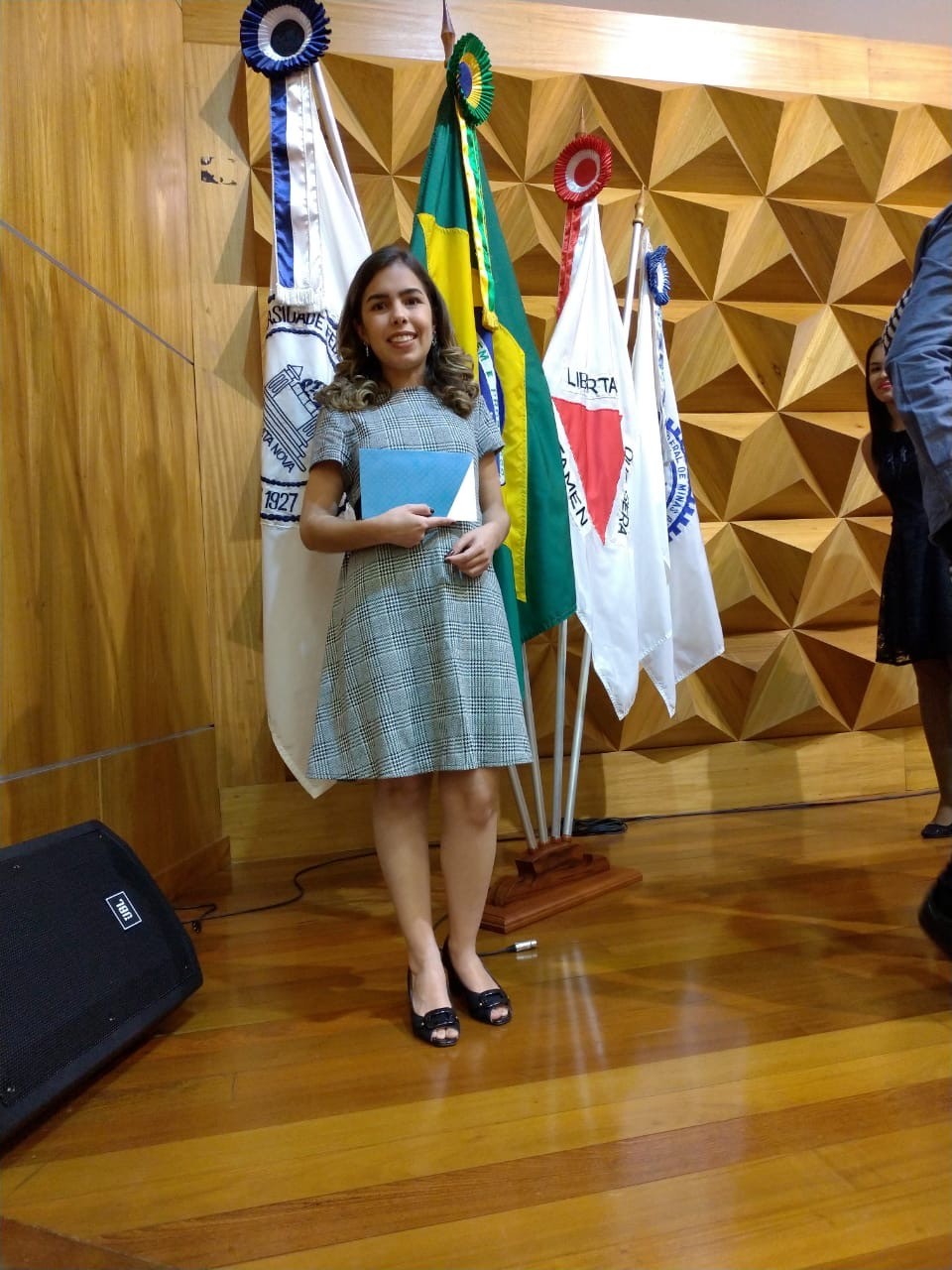 Mão segurando um livro em uma biblioteca universitária