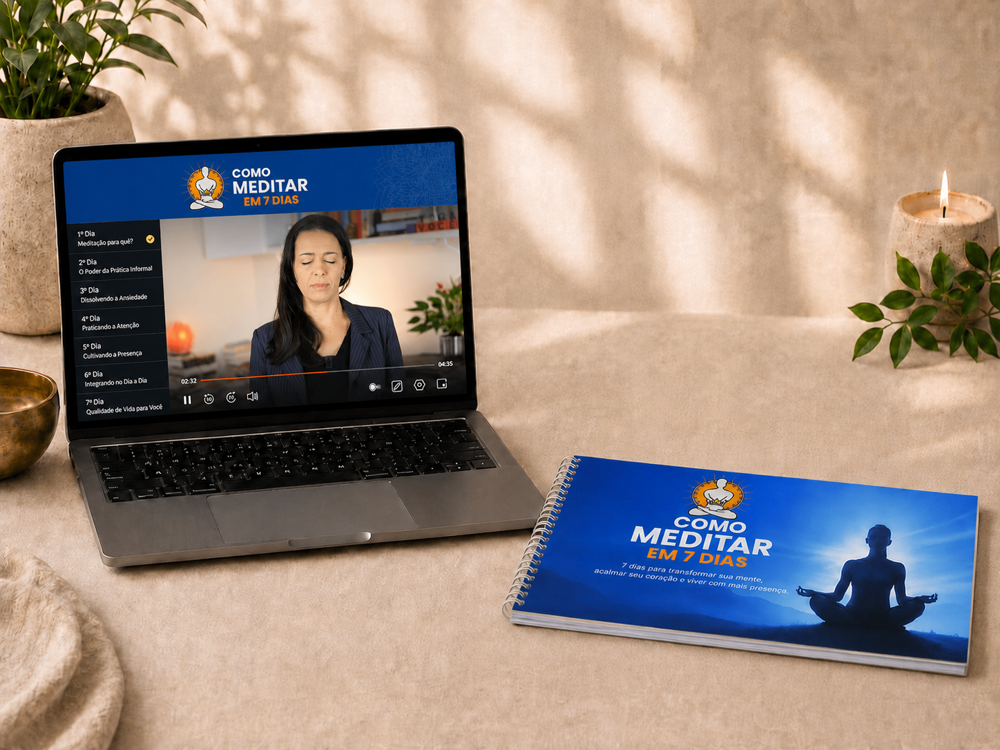 Cena acolhedora de prática de meditação em casa: laptop com aula guiada, cartilha azul, vela acesa e planta sobre tecido claro com luz quente